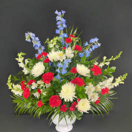 Red, white, and blue floral arrangement in a white vase