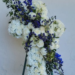 Large white floral cross with blue accents on an easel