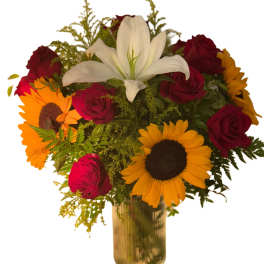 Bouquet of red roses, sunflowers, and a white lily in a gold vase