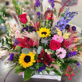 Colorful mixed bouquet with roses, lilies, sunflowers, and a butterfly accent