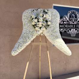 White floral standing spray on a wooden easel with roses and lilies