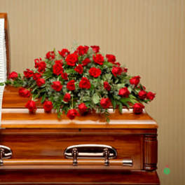 Red rose spray on top of a wooden casket