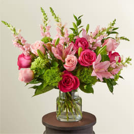 Pink roses and lilies arranged in a clear glass vase