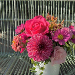 Pink and magenta flowers arranged in a white vase