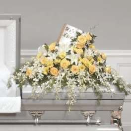 Yellow and white floral casket spray on a gray casket