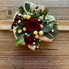 Red rose bouquet with white berries and ribbon on a wooden surface