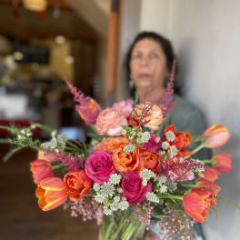 Handheld bouquet of orange, pink, and peach flowers