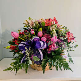 Mixed flower basket with pink, purple, and white blooms and a purple ribbon