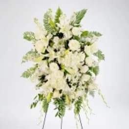 White floral standing spray with green foliage on a white background