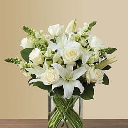 White lilies and roses arranged in a clear glass vase
