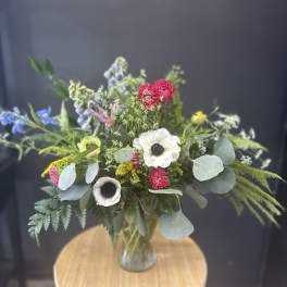 Mixed bouquet in a glass vase with white, pink, blue, and yellow flowers