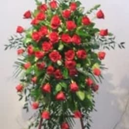 Standing spray of red roses on a white easel
