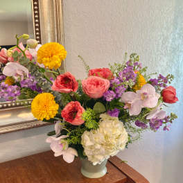 Colorful mixed flower arrangement in a pale vase on a table