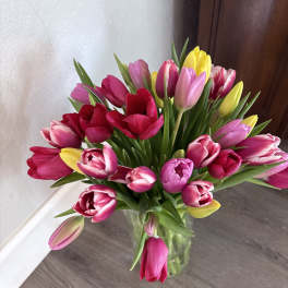 Bouquet of pink, red, and yellow tulips in a clear glass vase