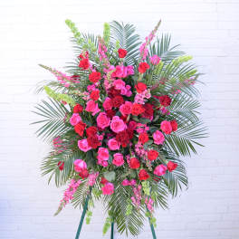 Large standing spray of pink and red roses with palm fronds