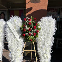 White angel wings floral tribute with red roses on an easel