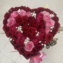 Heart-shaped box of red and pink roses with ribbon and butterfly accents