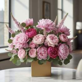 Pink peonies and roses arranged in a gold square vase