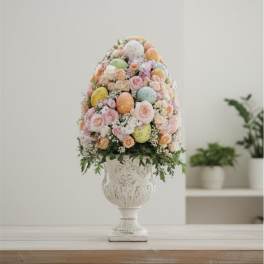 Pastel flower arrangement with decorated eggs in a white urn vase
