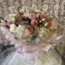 Bouquet of pink and white roses with hydrangeas wrapped in pale pink paper