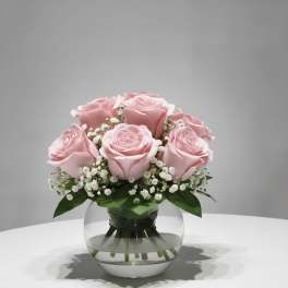 Pink roses arranged in a round glass vase with white filler flowers