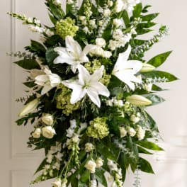 Tall white floral standing spray with lilies and roses on an easel