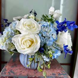 White roses and blue hydrangeas in a striped vase