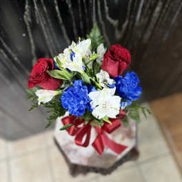 Bouquet of red roses, white alstroemeria, and blue carnations tied with a red ribbon