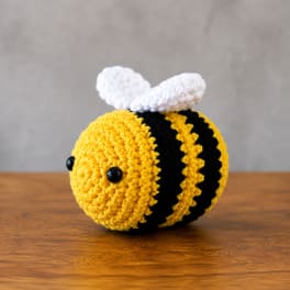 Crocheted bee plush with yellow and black stripes and white wings