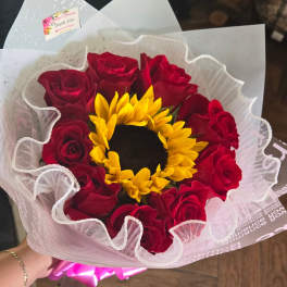 Bouquet of red roses with a yellow sunflower center wrapped in white paper