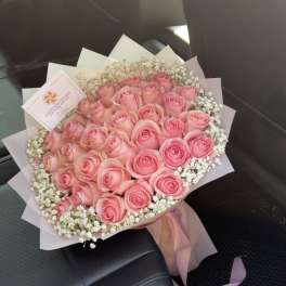 Bouquet of pink roses with white baby's breath and pink wrapping