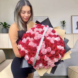 Large bouquet of red and pink roses wrapped in black and beige paper