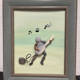 Framed pebble art of a musician playing guitar with musical notes