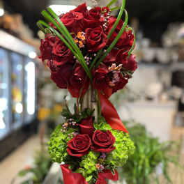 Tall arrangement of red roses with green accents and red ribbon