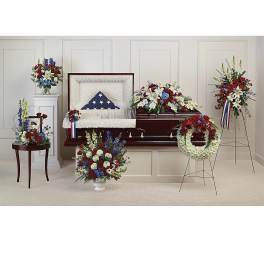 Casket surrounded by red, white, and blue funeral flower arrangements