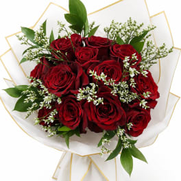 Bouquet of red roses with white filler flowers and green leaves in white wrap