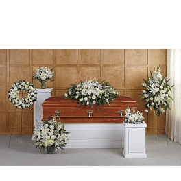 White funeral casket surrounded by white floral arrangements