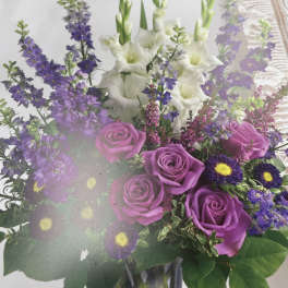 Bouquet of purple roses and white gladiolus in a glass vase