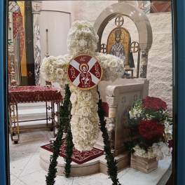 White floral cross standing in a church interior with red accents