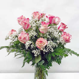 Pink and white roses arranged in a clear glass vase with baby's breath