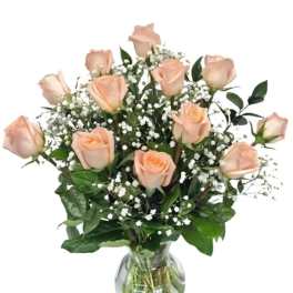 Peach roses arranged in a clear glass vase with baby's breath