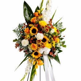 Standing floral spray with yellow, orange, and white blooms on a black easel