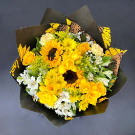 Bouquet of yellow roses, sunflowers, and white alstroemeria in black wrap
