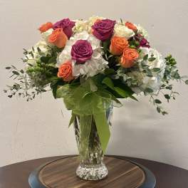 Bouquet of orange and magenta roses in a clear glass vase