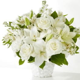White lilies and roses arranged in a white basket vase