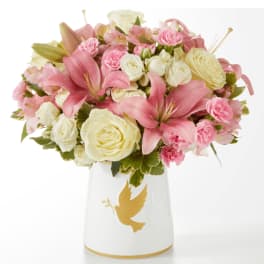 Pink and white flower arrangement in a white vase with a gold dove
