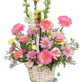 Pink and yellow mixed flowers arranged in a woven basket