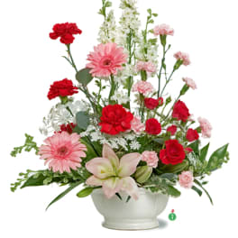Pink and red mixed flower arrangement in a white bowl vase