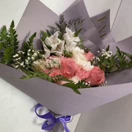 Bouquet of pink roses and white flowers wrapped in lavender paper