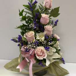 Pink roses and white lilies arranged with purple filler in a vase